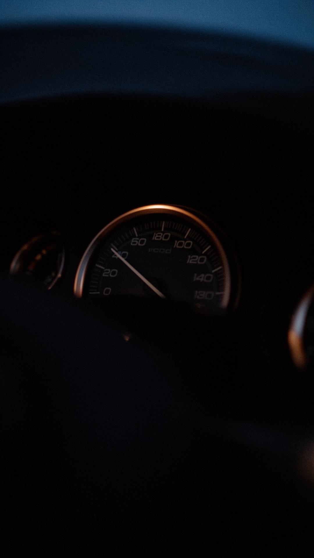 Bronze-rimmed analog tachometer dial in low light
